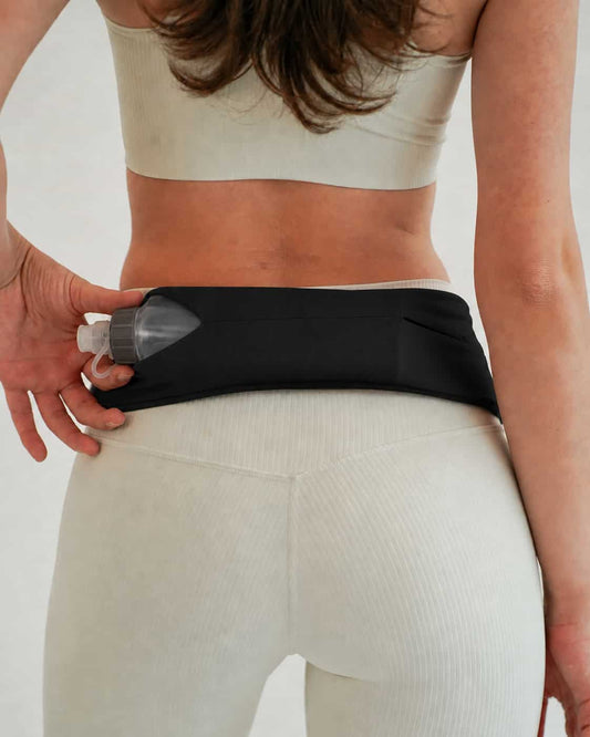 Vitaract Arc collapsible water bottle sliding into the side pocket of a black Vitaract running belt